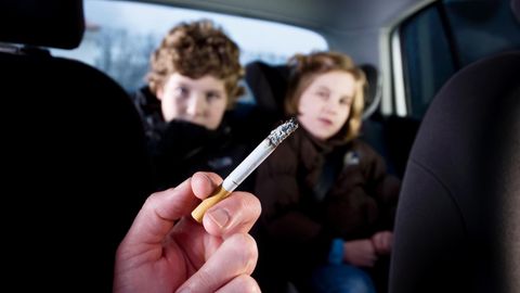 Rauchender Erwachsener mit Kindern im Auto