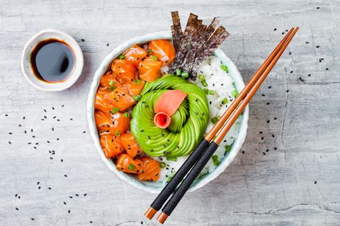 In dieser Schüssel befindet sich Lachs-Poke mit Algenblättern, Avocado, Sesam, Frühlingszwiebeln und Reis. 