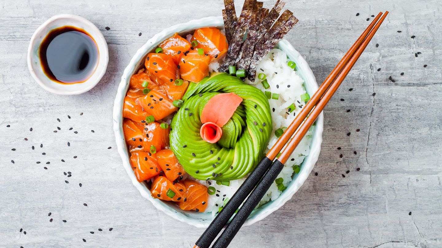 In dieser Schüssel befindet sich Lachs-Poke mit Algenblättern, Avocado, Sesam, Frühlingszwiebeln und Reis. 
