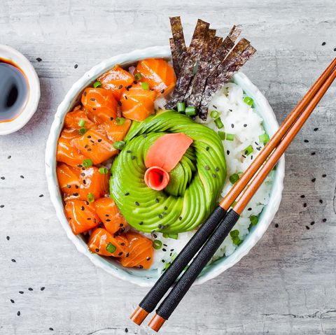 In dieser Schüssel befindet sich Lachs-Poke mit Algenblättern, Avocado, Sesam, Frühlingszwiebeln und Reis. 