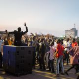 Menschen feiern und tanzen auf einem Platz.