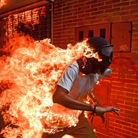 "Venezuela Krise" lautet der schlichte Titel des spektakulären Fotos, mit dem der Fotograf Ronaldo Schemidt jetzt den Titel für das Weltpressefoto des Jahres gewann. Das Bild zeigt den Demonstranten José Víctor Salazar Balza, der während der Proteste gegen Venezuelas Präsident Nicolás Maduro im Mai 2017 von Flammen erfasst worden war. Er überlebte mit schweren Brandwunden