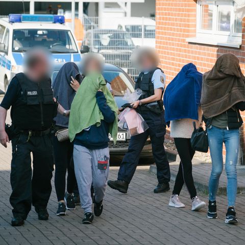 Beamte der Bundespolizei eskortieren Fraen aus einem Gebäude