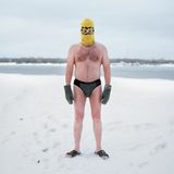 Mann steht in Badekleidung im Schnee