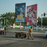 Ein Mann läuft in Acccra an Postern vorbei, die Prediger bewerben.