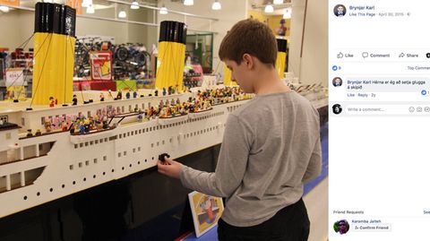 Der isländische Junge steht vor seinem Schiffsmodell und baut mit Legosteinen