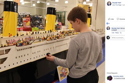 Der isländische Junge steht vor seinem Schiffsmodell und baut mit Legosteinen