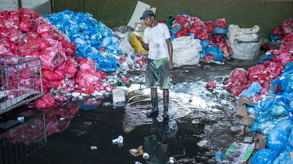 Forest Dump: Mann posiert mit Gewehr neben Haufen Müll und hält uns so den Spiegel vor