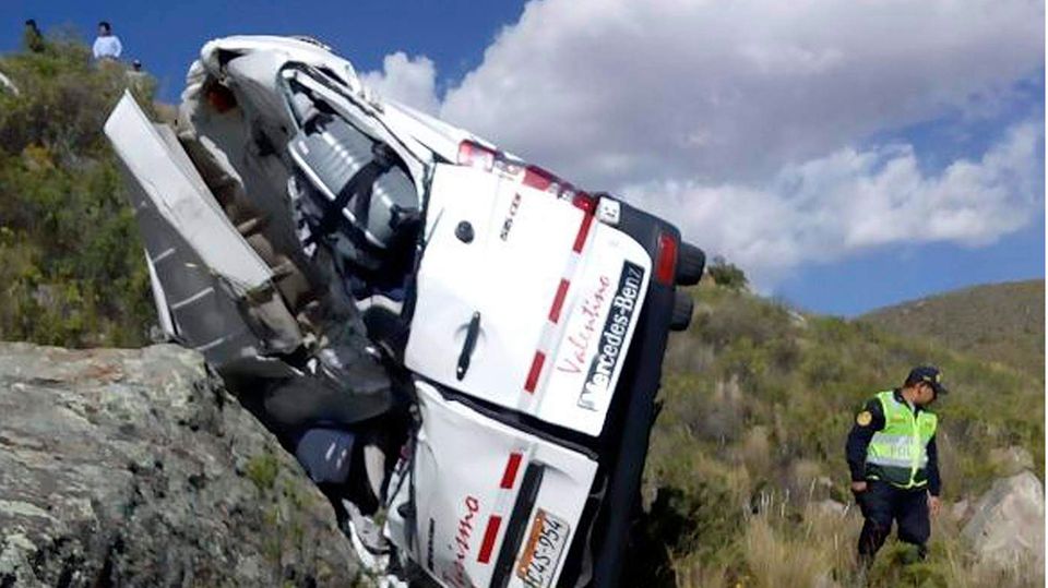 Busunfall Peru Das Foto zeigt einen Polizisten am Unfallort neben einem verunglückten Kleinbus einer Reisegruppe