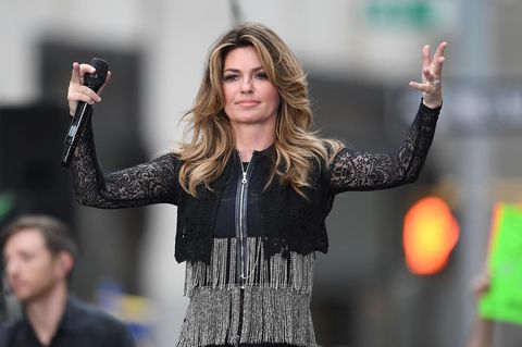 In schwarzer Bolero-Jacke steht Sängerin Shania Twain auf der Bühne, ein Mikro in der rechten Hand, und winkt ins Publikum