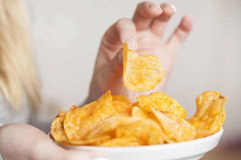 Eine Frau isst Chips aus einer Schale