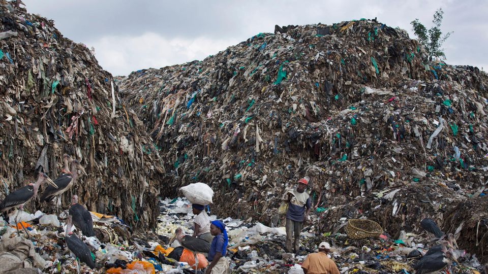 Menschen durchsuchen im Dandora Slum in Nairobi einen Müllberg nach wiederverwertbaren Gegenständen. Menschen durchsuchen im Dandora Slum in Nairobi einen Müllberg nach wiederverwertbaren Gegenständen.