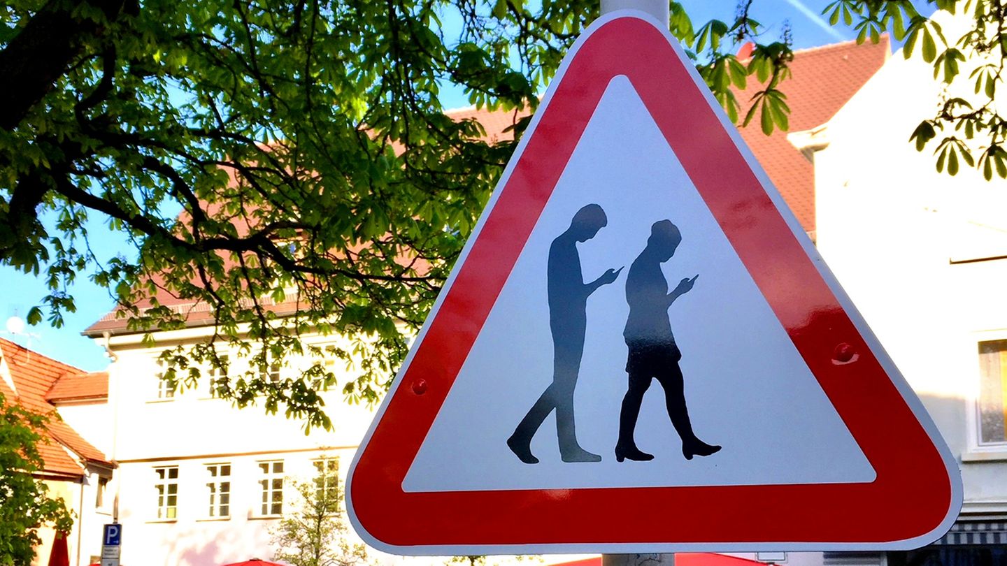 Verkehrsschild rotes Dreieck mit zwei Figuren, die beim Gehen auf das Smartphone schauen