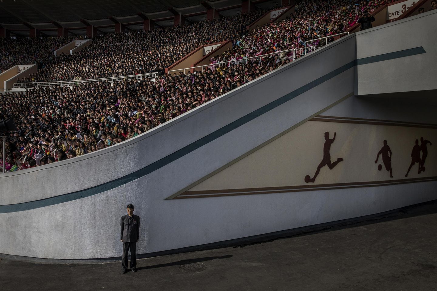 Ausgezeichnete Fotografie: Fotograf: Roger Turesson 9. April 2017 3. Preis im Segment "Einzelfotos" Eine Menschenmenge wartet auf den Start des Pjöngjang-Marathons im Kim-il-sung-Stadion, ein Funktionär bewacht den Ausgang, in Pjöngjang, Nordkorea. Über 50.000 Zuschauer hatten sich zu diesem Anlass eingefunden. Weitere tausende Zuschauer säumten die Straßen der nordkoreanischen Hauptstadt. Die Strecke führte die Läufer an Wahrzeichen wie dem Triumphbogen, den Kim-Il-sung-Platz und dem großen Opernhaus entlang. Nordkorea ist eine der isoliertesten und verschlossensten Nationen der Welt. Es ist ein Führer-Kult um die Kim-Dynastie entstanden, von Kim Il-sung (dem Großen Führer) über seinen Sohn Kim Jong-il (den Lieben Führer) zum Enkel, dem jetzigen Obersten Führer Kim Jong-un. Das Land wird unter strenger staatlicher Kontrolle regiert. Die Medien werden stark zensiert. Ausländische Pressevertreter werden nicht zugelassen, oder wenn dies doch der Fall ist, ständig begleitet. Fotograf: Roger Turesson 9. April 2017 3. Preis im Segment "Einzelfotos" Eine Menschenmenge wartet auf den Start des Pjöngjang-Marathons im Kim-il-sung-Stadion, ein Funktionär bewacht den Ausgang, in Pjöngjang, Nordkorea. Über 50.000 Zuschauer hatten sich zu diesem Anlass eingefunden. Weitere tausende Zuschauer säumten die Straßen der nordkoreanischen Hauptstadt. Die Strecke führte die Läufer an Wahrzeichen wie dem Triumphbogen, den Kim-Il-sung-Platz und dem großen Opernhaus entlang. Nordkorea ist eine der isoliertesten und verschlossensten Nationen der Welt. Es ist ein Führer-Kult um die Kim-Dynastie entstanden, von Kim Il-sung (dem Großen Führer) über seinen Sohn Kim Jong-il (den Lieben Führer) zum Enkel, dem jetzigen Obersten Führer Kim Jong-un. Das Land wird unter strenger staatlicher Kontrolle regiert. Die Medien werden stark zensiert. Ausländische Pressevertreter werden nicht zugelassen, oder wenn dies doch der Fall ist, ständig begleitet.