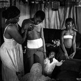Fotografin: Heba Khamis     6. November - 7. Dezember 2016    1. Preis im Segment "Serien"  In Kamerun ist die Tradition des Brustbügelns verbreitet.  Dabei werden die Brüste junger Mädchen unter Druck mit erhitzten Gegenständen gerieben, um das Wachstum der Brüste zu hemmen oder zu unterdrücken. Man glaubt, dass die Mädchen dadurch langsamer heranreifen und vor Vergewaltigungen oder sexueller Belästigung geschützt werden. Normalerweise wird dies von der Mutter oder einer älteren Verwandten des Mädchens getan. Je nach Region geht man dabei anders vor. Manchmal werden die Brüste mit einem Gurt abgebunden, oder es wird ein erhitzter Mahlstein, Spatel oder Stößel auf die Brüste gedrückt oder gerieben.  Hier massiert Veronica (28) die Brüste ihrer Tochter Michelle (10), ihre anderen Kinder schauen zu.