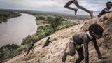 Fotograf: Fausto Podavini     24. Juli 2011 - 24. November 2017    2. Preis     Der Gibe-III-Staudamm im Omo-Fluss in Äthiopien hat nicht nur Auswirkungen für die Bewohner des Omo-Tals, sondern auch auf die Anwohner des Turkana-Sees in Kenia (in den der Omo einmündet). In diesem Tal leben Menschen acht verschiedener Ethnizitäten in einem empfindlichen Gleichgewicht mit der Umwelt. Für ihre Lebensmittelversorgung sind sie auf den Fluss angewiesen.    Die äthiopische Regierung sieht diesen Damm als gewinnbringende Wasserkraftanlage, Quelle von Wasser für die großflächige Landwirtschaft und als Touristen-Attraktion und bestreitet Vorwürfe über die negativen Umweltauswirkungen. Kritiker weisen auf die abnehmende Biodiversität, den sinkenden Wasserstand im Turkana-See, die geringeren Ablagerungen von fruchtbarem Boden durch die jährlichen Überschwemmungen und die Vertreibung traditioneller Völker hin.    Der Fotograf besuchte das Omo-Tal, um mit der Fotostrecke einen gedanklichen Anstoß zu geben, wie Investitionen das Gleichgewicht von Mensch und Umwelt gefährden können. In dieser Szene spielen indigene Karo-Kinder im Sand am Ufer des Omo-Flusses. Die Karo sind auf den Fluss angewiesen: auf Fisch und auf die in dem fruchtbaren Überschwemmungsboden angebauten Nutzpflanzen. Der Wald im Hintergrund wurde abgeholzt, um Platz für den Baumwollanbau zu schaffen ...