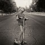 Mädchen mit Roller steht auf Straße