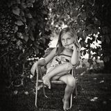 Mädchen sitzt in Kinderstuhl im Garten