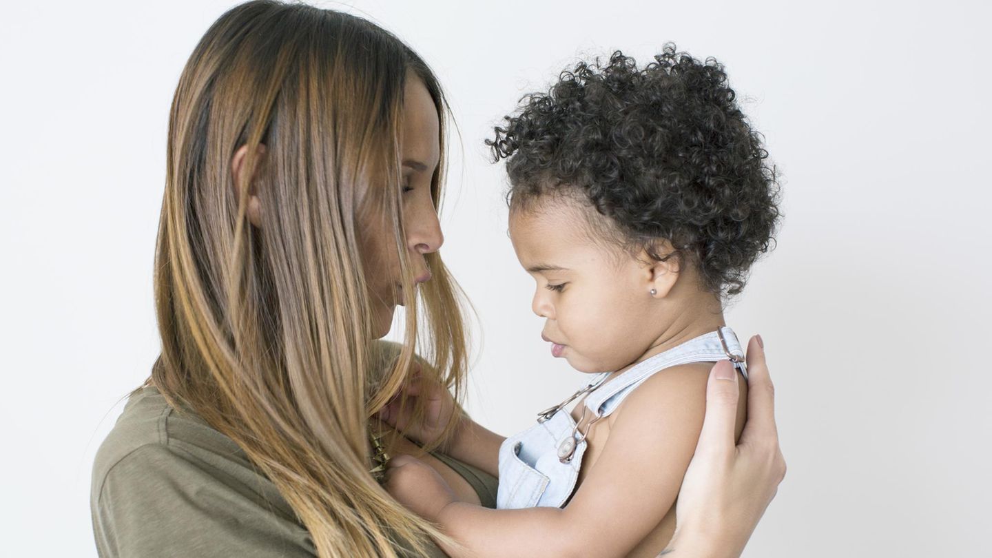 Eine weiße Mutter mit einem schwarzen Baby im Arm