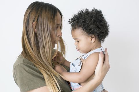 Eine weiße Mutter mit einem schwarzen Baby im Arm