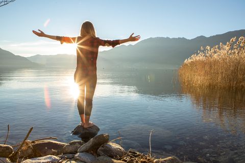 Eine Frau steht am See und entspannt