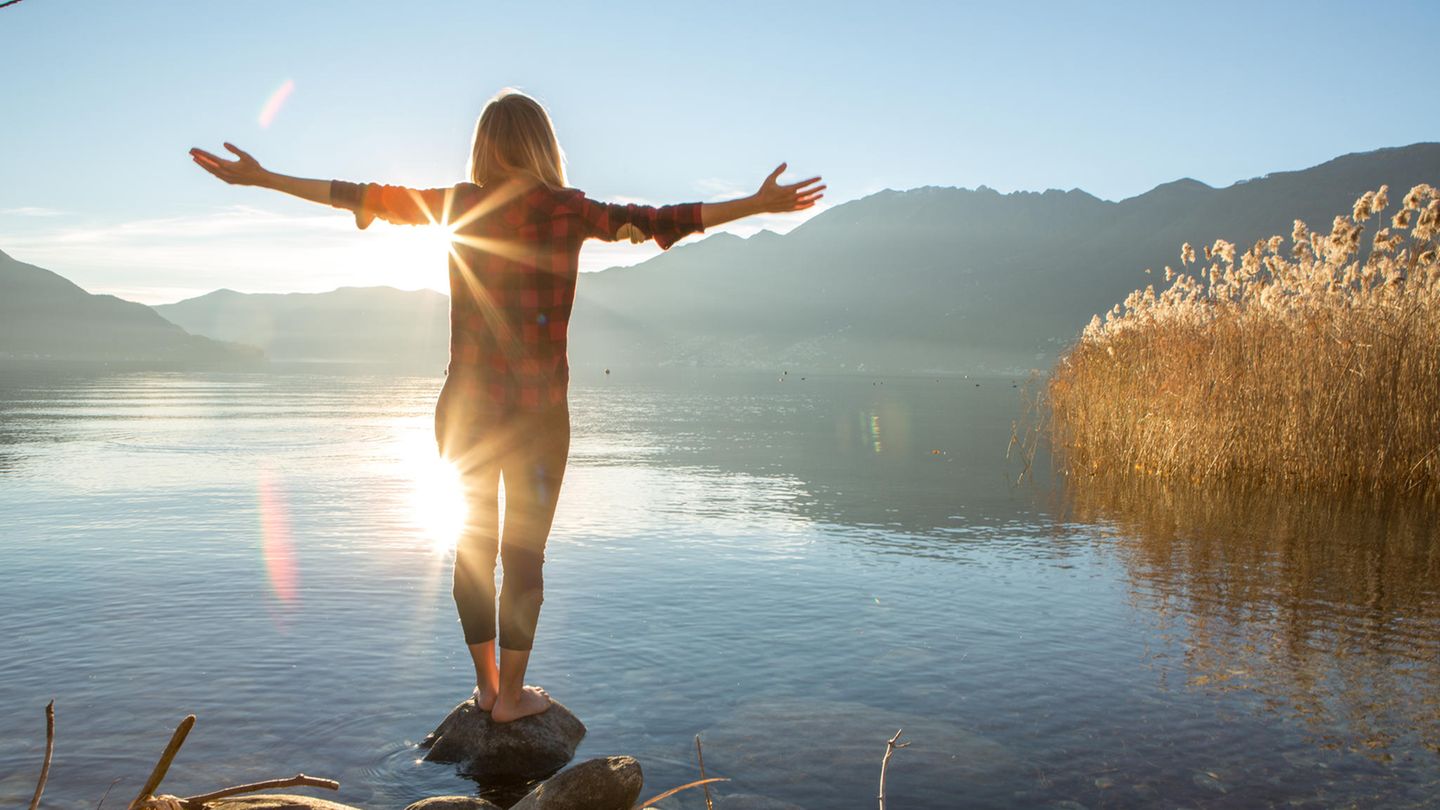 Eine Frau steht am See und entspannt