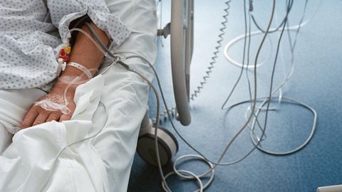 Ein Patient mit einer Infusion im Arm liegt in einem Krankenhausbett