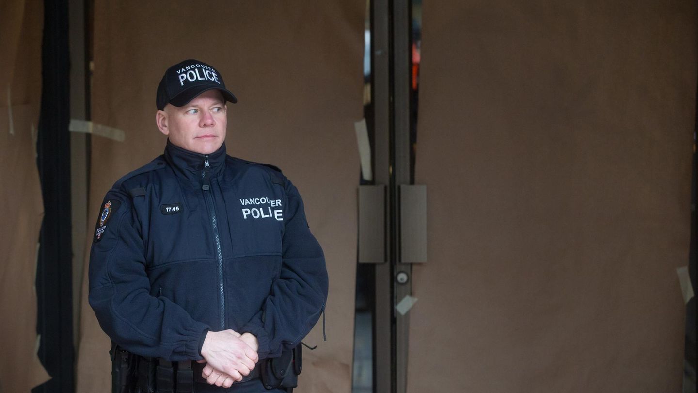 Ein Polizist steht vor einer mit blickdichtem Papier beklebten Glastür.