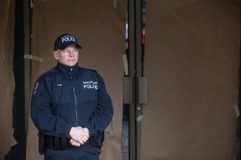 Ein Polizist steht vor einer mit blickdichtem Papier beklebten Glastür.