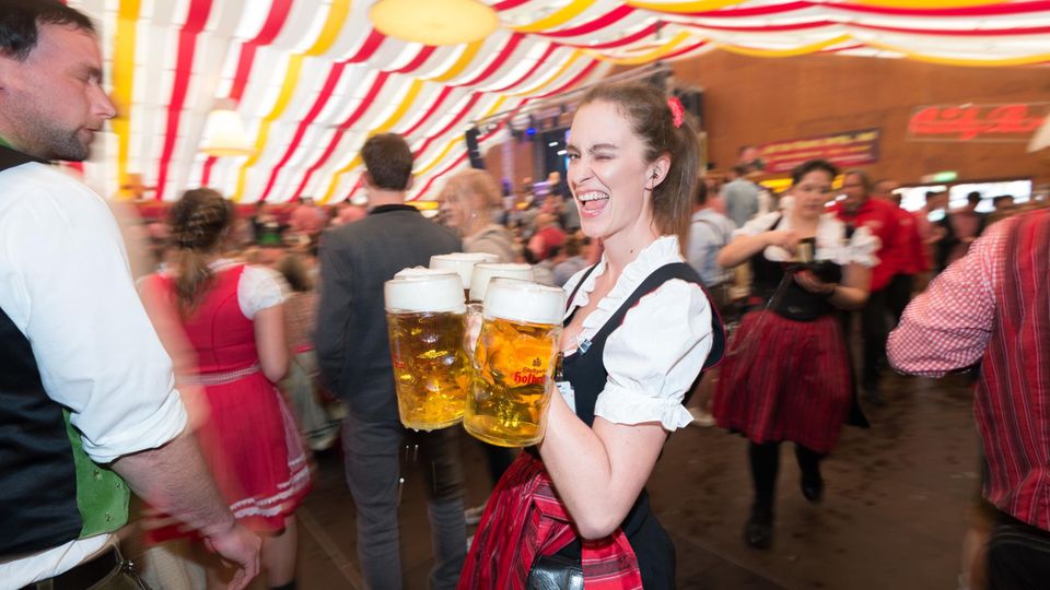 Eine Kellnerin mit Bierkrügen inmitten einer Menschenmenge beim Stuttgarter Frühlingsfest.