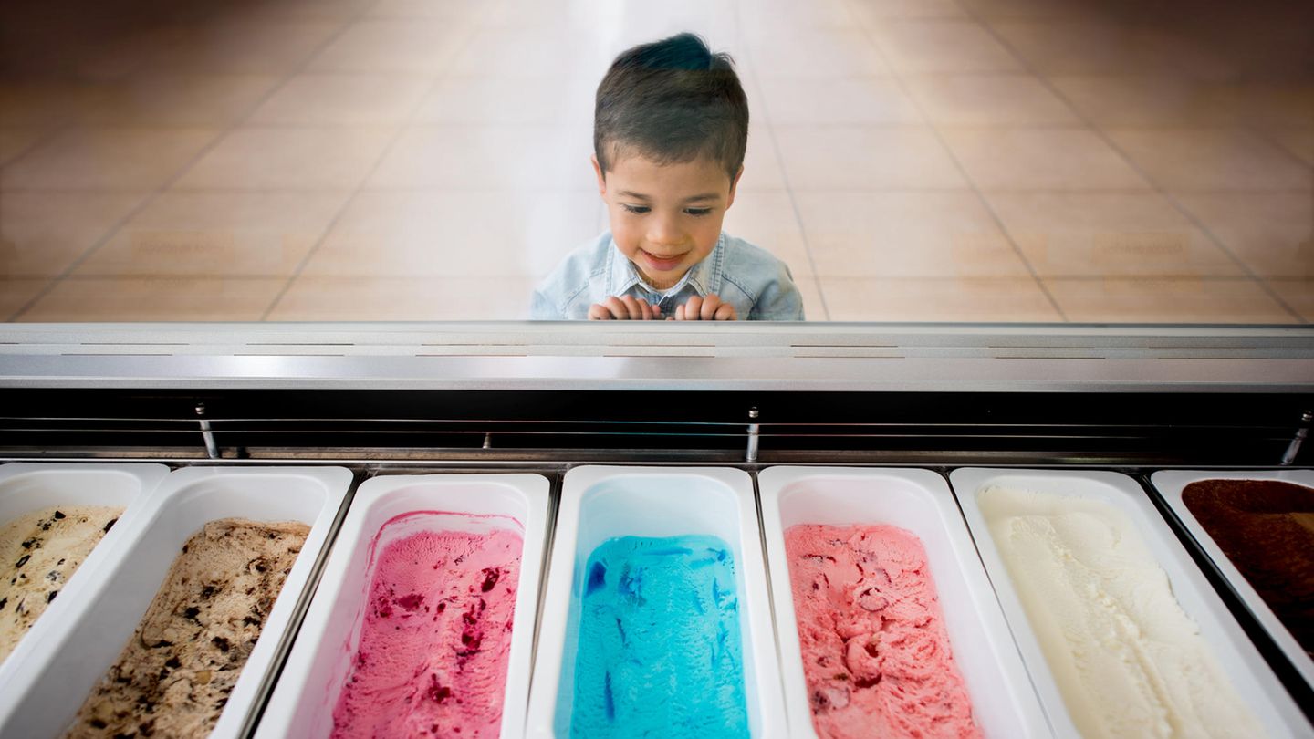 Ein kleiner Junge steht vor bunten Eissorten