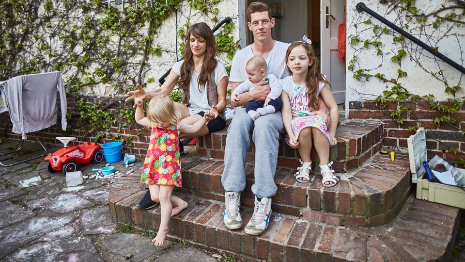 Tatjana und René Masuhr mit ihren drei Kindern, Berlin  Familie Masuhr hat kapituliert. Vor drei Wochen sind die fünf rausgezogen – nicht mit wehenden Fahnen, sondern mit flatternden Herzen. Widerwillig. Buckower Damm, ein Häuschen zur Miete, klein und alt. Rechts türmen sich die Betonburgen von Berlins Problembezirk Neukölln, links liegt Brandenburg. Jwd, wie der Berliner sagt, janz weit draußen. Das war nicht ihr Plan, damals vor zehn Jahren, als Tatjana und René zum Studium nach Berlin kamen. Die beiden Ostfriesen wollten: das Leben, Friedrichshain, Trendbezirk. Sie fanden: drei Zimmer auf 60 Quadratmetern für 520 Euro warm. Perfekt für zwei, okay für drei, zu klein für vier. Mia kam in die Schule, Yara lernte laufen, die Eltern gingen auf Wohnungssuche. Als Emil sich ankündigte, wurde es dringend. "Mit der Zeit erweitert man den Radius, schraubt das Budget nach oben und schluckt die Enttäuschungen runter", sagt Tatjana. Der Markt – leer gefegt. "Man findet kaum Angebote, die man bezahlen kann oder will", sagt René. Und wenn doch, hörten sie: Für drei Kinder ist die Wohnung eigentlich zu klein. Oder: Für Ihr Einkommen ist die Wohnung eigentlich zu teuer. Im Moment leben sie von einem Gehalt, das René als Projektmanager verdient, Tatjana, sonst Sozialarbeiterin, bekommt Elterngeld. Mit den Monaten zog René den Radius auf, immer weiter – und fand dieses Häuschen, weinberankt, mit kleinem Garten, 1250 Euro kalt. Dafür müssen sie einiges machen, nicht nur am Haus. Das ganze Leben muss sich neu sortieren. Mias alte Schule? 45 Minuten Fahrzeit. Der nächste Spielplatz? Fast zwei Kilometer entfernt. Freunde treffen, ganz spontan ins Café? "Ach, es ist schon verdammt weit draußen", sagt Tatjana und seufzt.