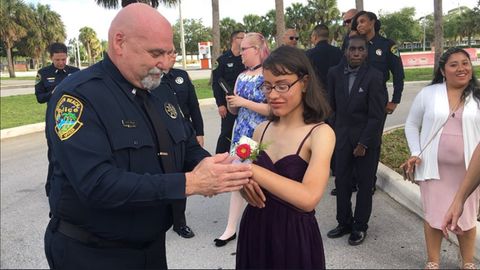 Ein Polizist bindet einer Schülerin ein Blumensträußchen ans Handgelenk