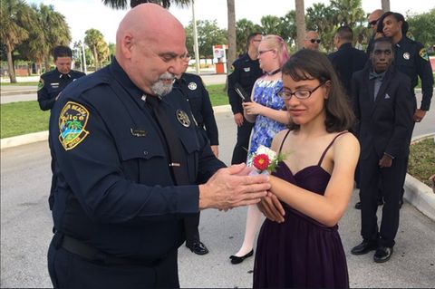 Ein Polizist bindet einer Schülerin ein Blumensträußchen ans Handgelenk
