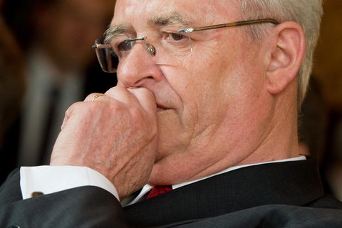 Ex-VW-Chef Martin Winterkorn schaut besorgt und hält sich die linke Faust vor den Mund. Er trägt Anzug und randlose Brille