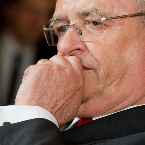 Ex-VW-Chef Martin Winterkorn schaut besorgt und hält sich die linke Faust vor den Mund. Er trägt Anzug und randlose Brille