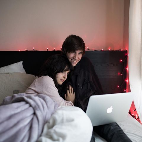 Ein Paar liegt mit Laptop im Bett