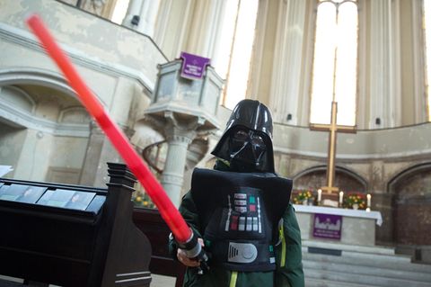 Ein Mann im Darth-Vader-Kostüm und einem Laserschwert in der Hand