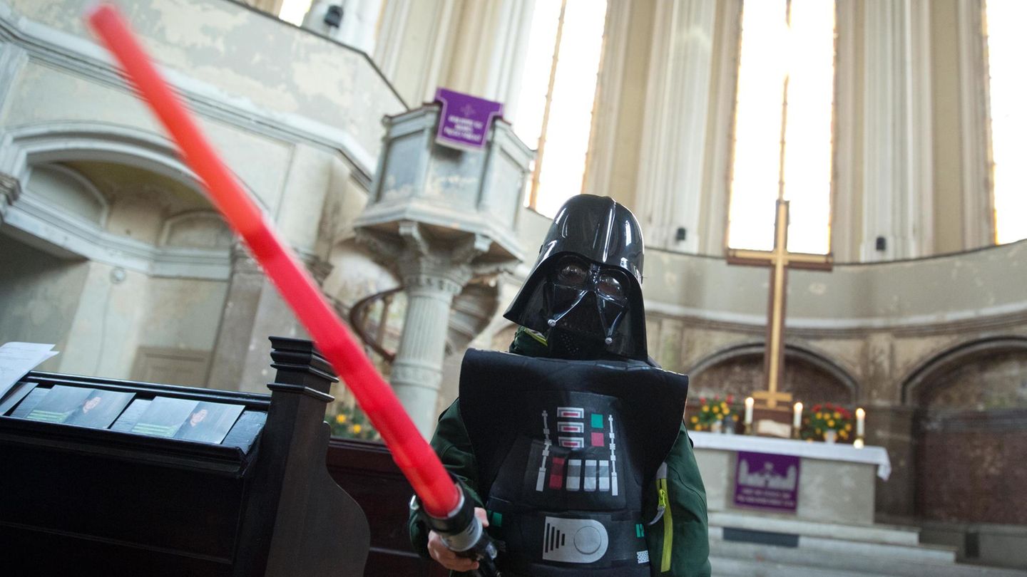 Ein Mann im Darth-Vader-Kostüm und einem Laserschwert in der Hand