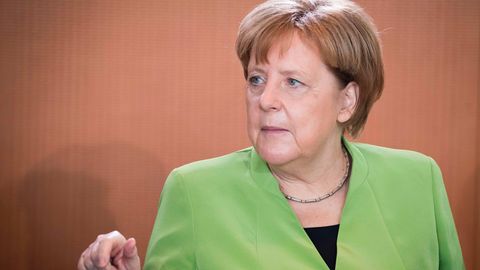 In einem frühlingsgrünen Blazer sitzt Bundeskanzlerin Angela Merkel am Kabinettstisch und gestikuliert mit der rechten Hand