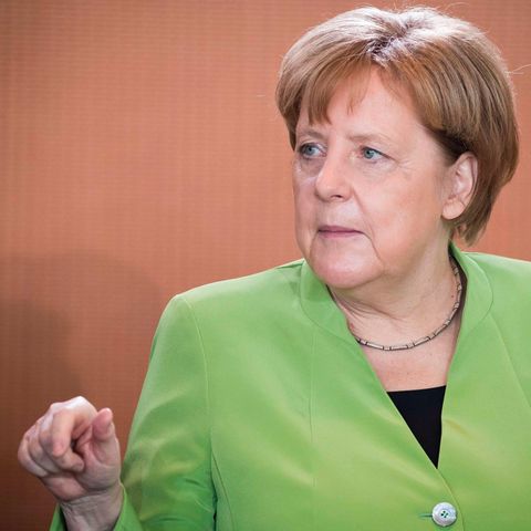 In einem frühlingsgrünen Blazer sitzt Bundeskanzlerin Angela Merkel am Kabinettstisch und gestikuliert mit der rechten Hand