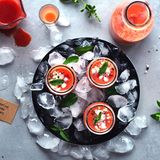 2 in 1: Deko und Vorspeise  Neben Blumen, Gestecken, Vasen, Lichtern und Kerzen können auch die Gänge eines Menüs den Tisch wunderbar schmücken. Für eine Sommerparty oder einen lauen Abend auf dem Balkon mit Freunden bieten sich zum Beispiel kleine Shot-Gläser oder Mini-Fläschchen (bis zu 100 ml) an, in denen selbstgemachte Gazpacho oder eine kalte Gemüsesuppe zum Trinken serviert werden. Sie dürfen wahlweise direkt am Platz neben den Tischkärtchen stehen oder bei lockeren Gartenfesten auch quer auf dem Tisch verteilt sein, sodass sich jeder etwas nehmen kann. Wer mag, bereitet gleich Suppen oder Drinks in zwei, drei verschiedenen Farben zu und serviert in unterschiedlich geformten Fläschchen und Schnaps-Gläsern: So passt der Welcome-Drink auch gleich noch zum Farb-Konzept des Abends!