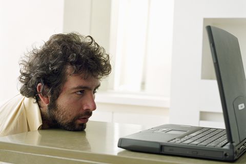 Ein Mann schaut resigniert auf seinen Laptop-Bildschirm