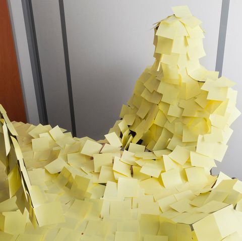 Ein Mann sitzt an einem Schreibtisch voll geklebt mit Post-Its