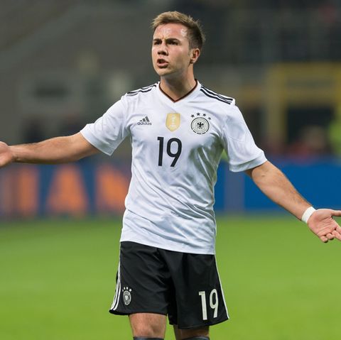 Mario Götze steht mit ausgebreiteten Armen im Nationaltrikot auf dem Fußballplatz und schaut verärgert