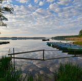 Groß Schauener See - Im brandenburgischen Kanada  Am Steg dümpelt ein Ruderboot, der Wind kräuselt Wellen über den Groß Schauener Sees. Die Sonne steht tief, man sitzt unter einer Waldkiefer, isst ein Stück geräucherten Aal aus der örtlichen Fischerei, fühlt sich wie in Kanada – aber nicht 50 Kilometer entfernt von Berlin-Mitte. Die Naturlandschaft Groß Schauener Seen hat der verstorbene Tierfilmer Heinz Sielmann geschaffen, Fischotter und Fischadler sollten eine Heimat finden, Kraniche und Kormorane auch. Wer länger als einen Tag im brandenburgischen Kanada verweilen will, mietet sich einfach in der Fischerei ein. Die Hauptstadt ist Lichtjahre entfernt.  www.koellnitz.de