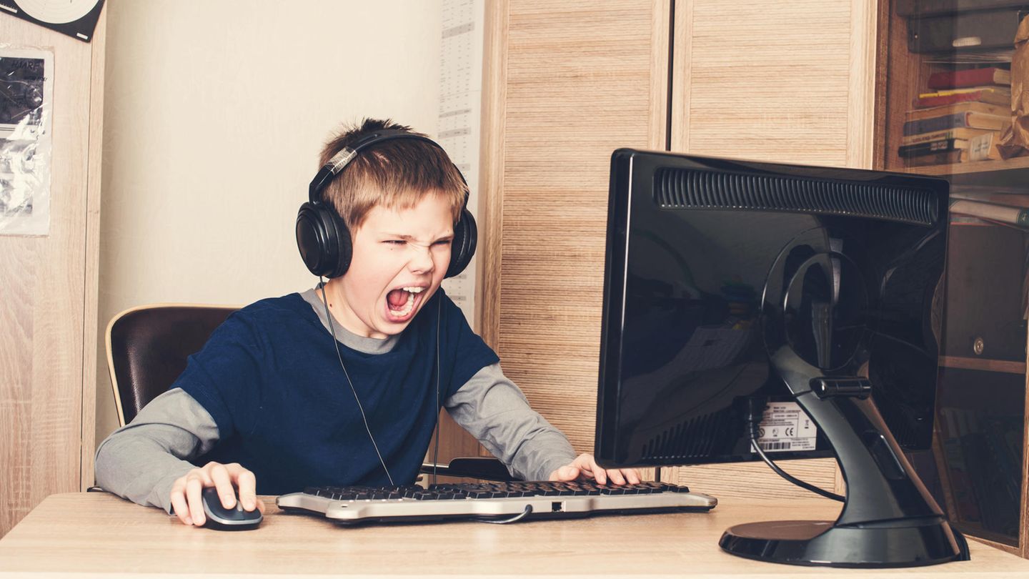 Eine Junge sitzt mit Kopfhören am Computer