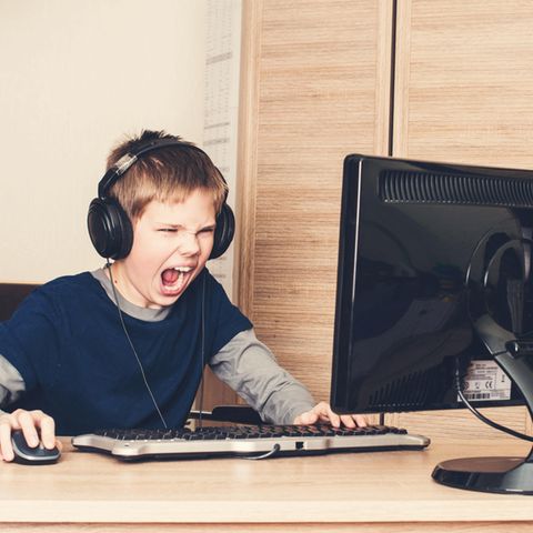 Eine Junge sitzt mit Kopfhören am Computer