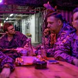 Bundeswehrsoldaten und Reporter Frederik Seeler sitzen an einem Tisch und trinken Bier