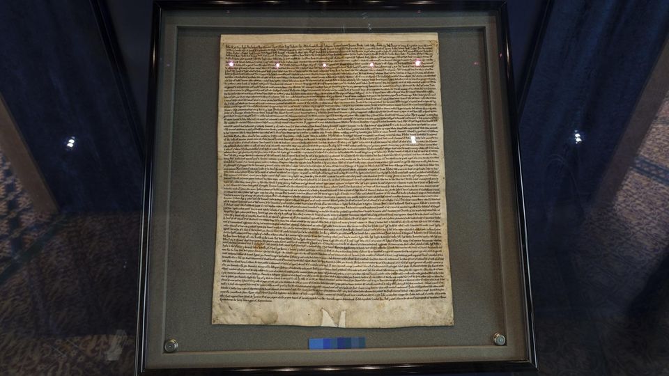 Magna Carta In einer dunkel gerahmten Vitrine liegt ein eng beschriebenes Stück Pergament: die Magna Carta